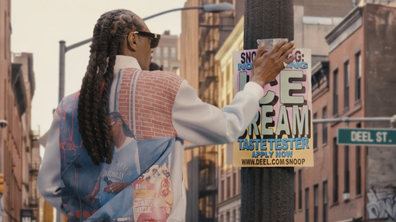 Snoop Dogg pasting a poster to a street pole.